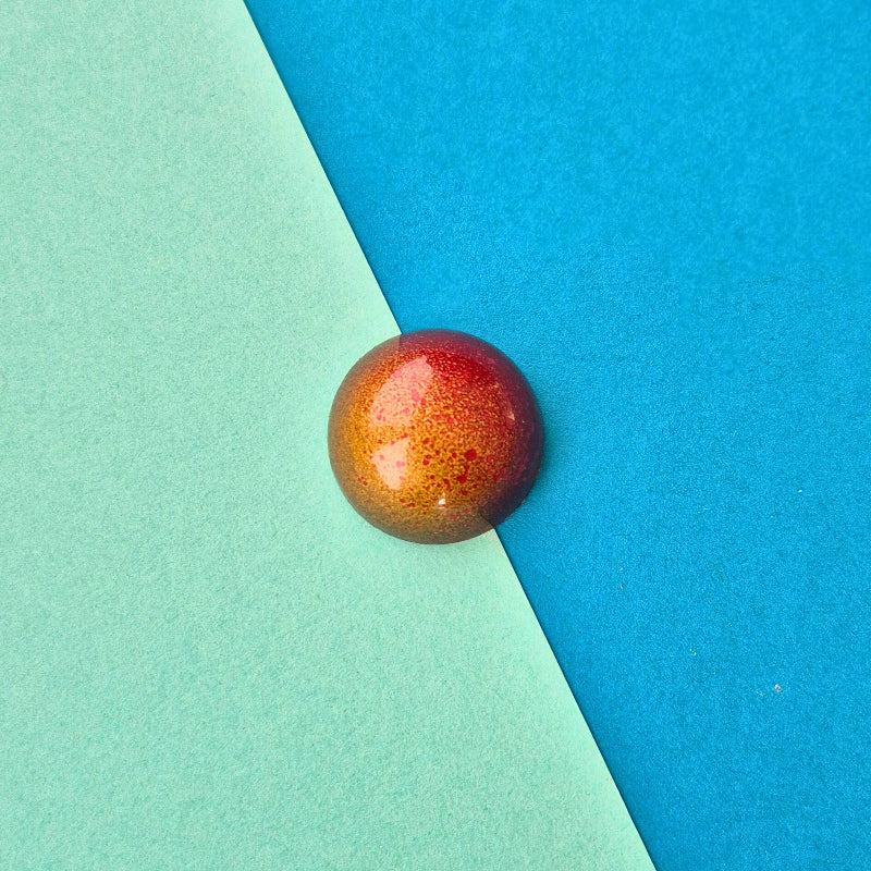 Handgegossene Praline Mango-Himbeere in dunkler Schokolade, milchfrei, gold-rot