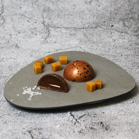 Angeschnittene Praline mit Vollmilchschokolade als Hülle und cremigerm Salzkaramell als Füllung.