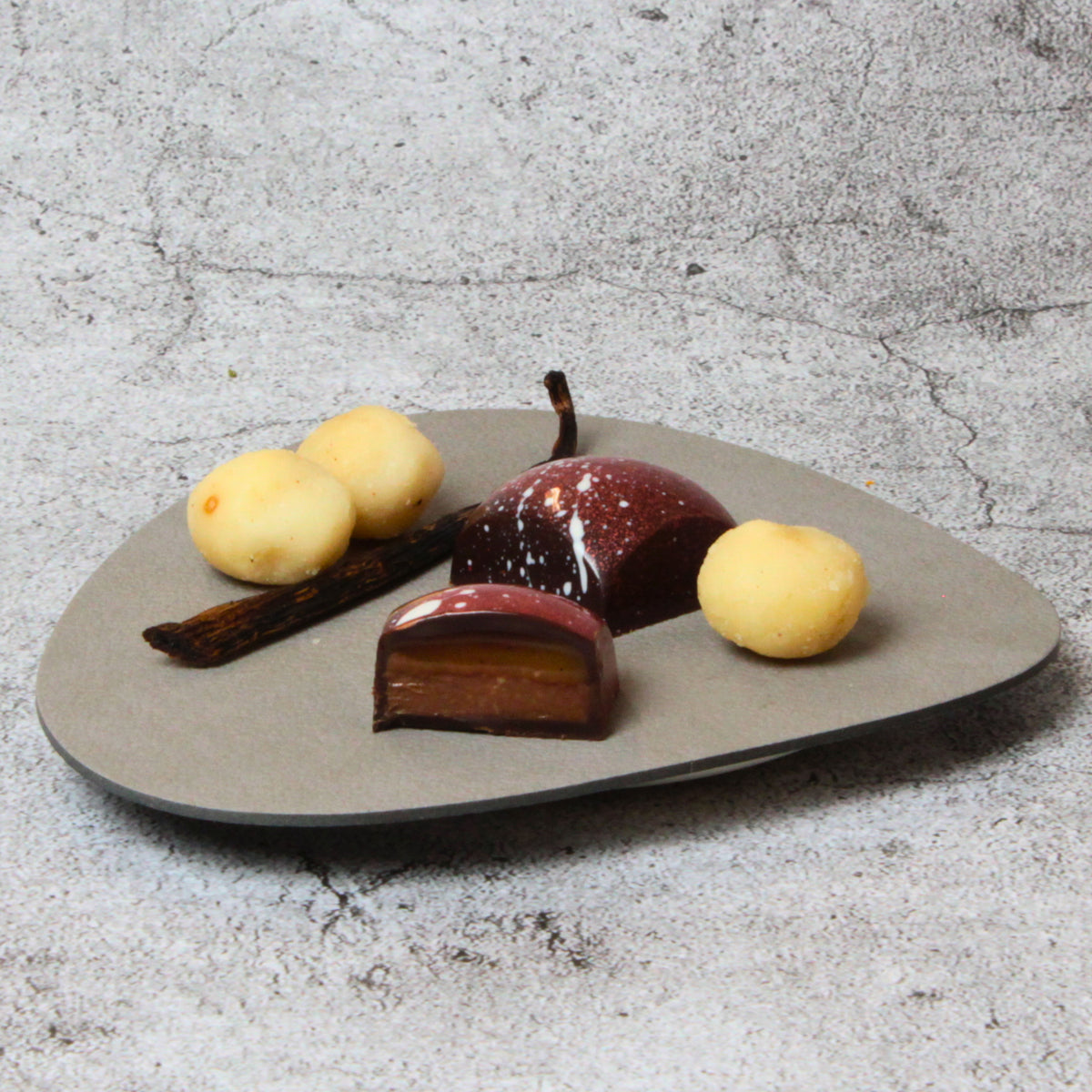 Macadamia-Vanillekaramell-Praline - cremiges Vanillekaramell auf Macadamia-Nougat, umhüllt mit dunkle Schokolade