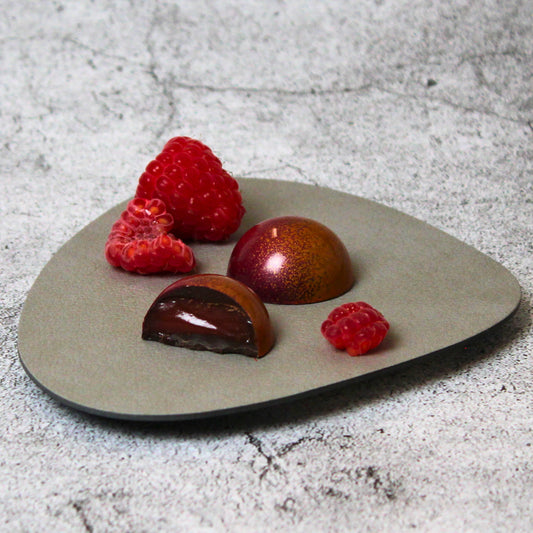 Fruchtige Praline in dunkler Schokolade gefüllt mit einer frischen Mango-Himbeer-Creme