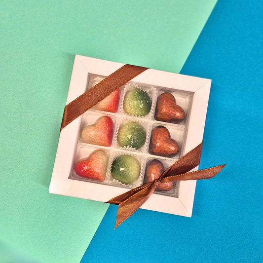Pralinenbox Sweet Diamonds - neun handgegossene Pralinen in Herz-Diamantform und Halbkugel-Diamantform. Dorten: Vanille-Erdbeere, Pistazie-Joghurt und Mango-Himbeere - verpackt in einer weißen 9er Pralinenschachtel, versehen mit Schleife