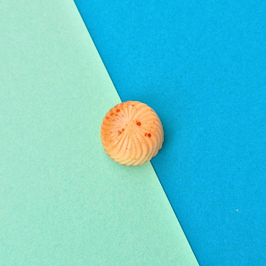 Handgegossene Praline Maracuja hoch 2 mit zwei unterschiedlichenMaracuja-Füllungen, designt in orange und gold