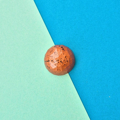 Handgegossene Salzkaramell-Praline in runder Diamantform, schwarz gesprenkelt und bronze