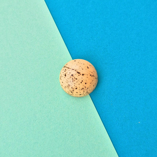 Handgegossene Praline Tahiti-Vanille in weißer Schokolade, schwarz gesprenkelt, edel schlicht
