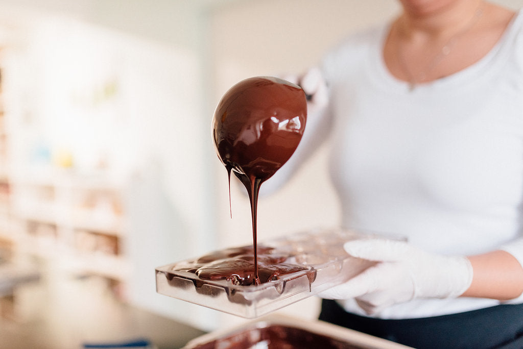 EIne Pralinenform wird mit Schokolade ausgegossen