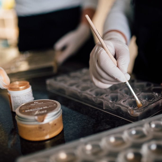 Pralinenformen werden mit Goldstaub geschminkt